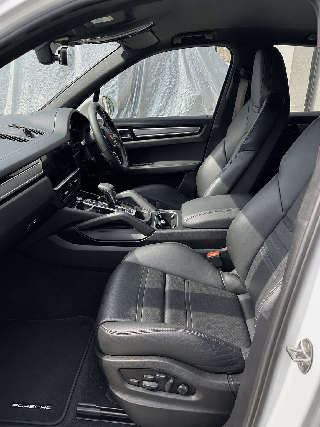 Detailed Porsche Cayenne front cabin with conditioned black leather seats and spotless carpets